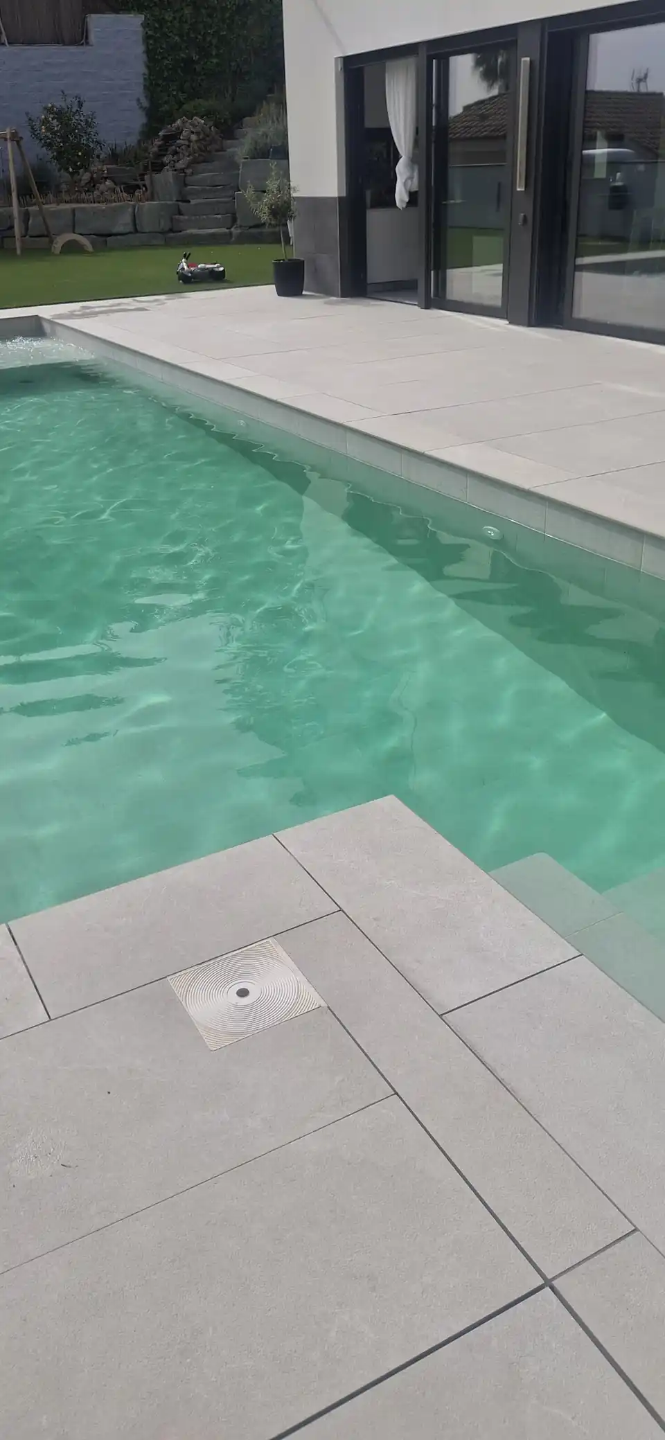 Piscina de agua clara con borde de piedra gris